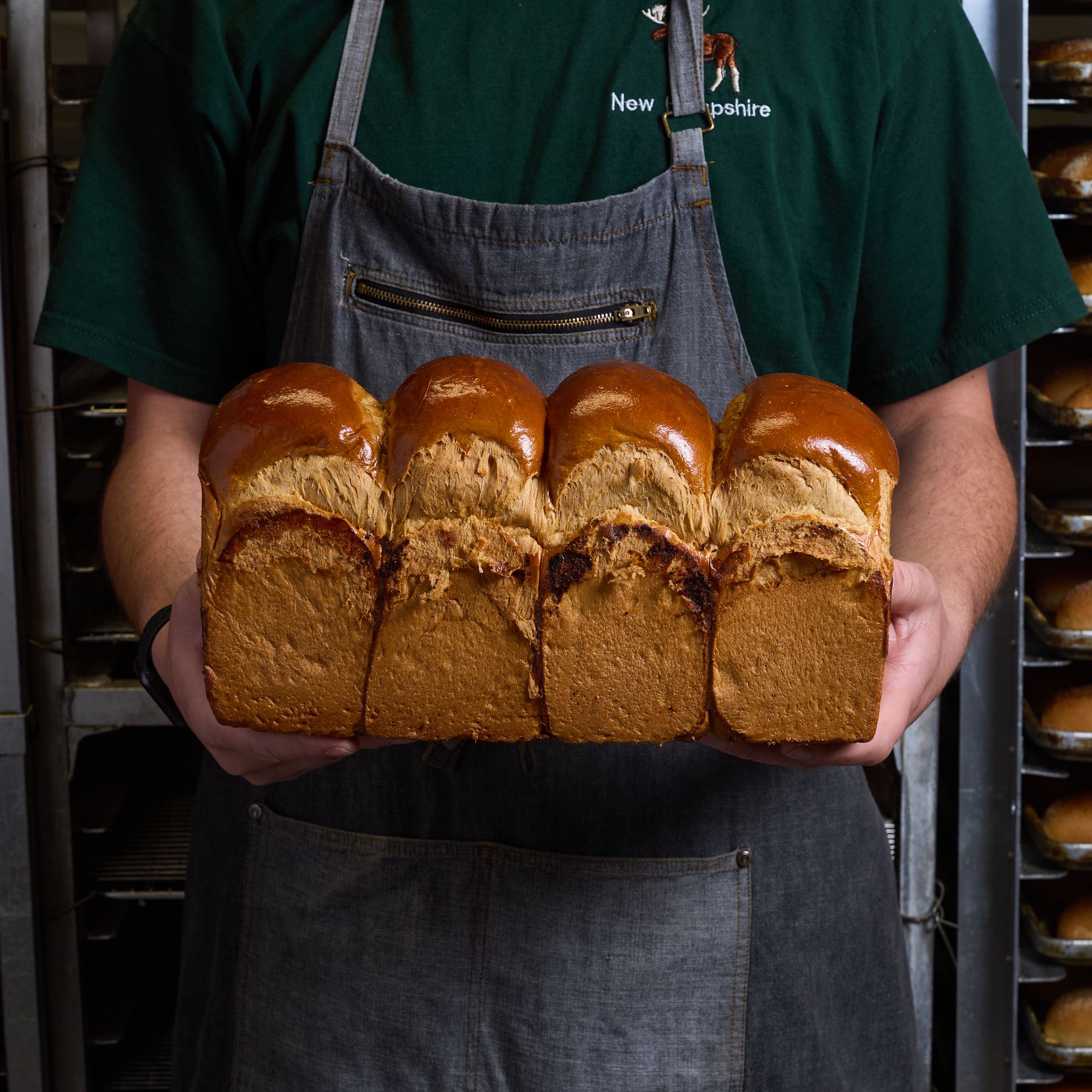 Baker holding a fresh cut peaked milk bread loaf